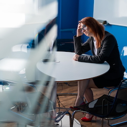 Managing Unconscious Bias at Work: Business professional seated thoughtfully at a table in a modern office setting