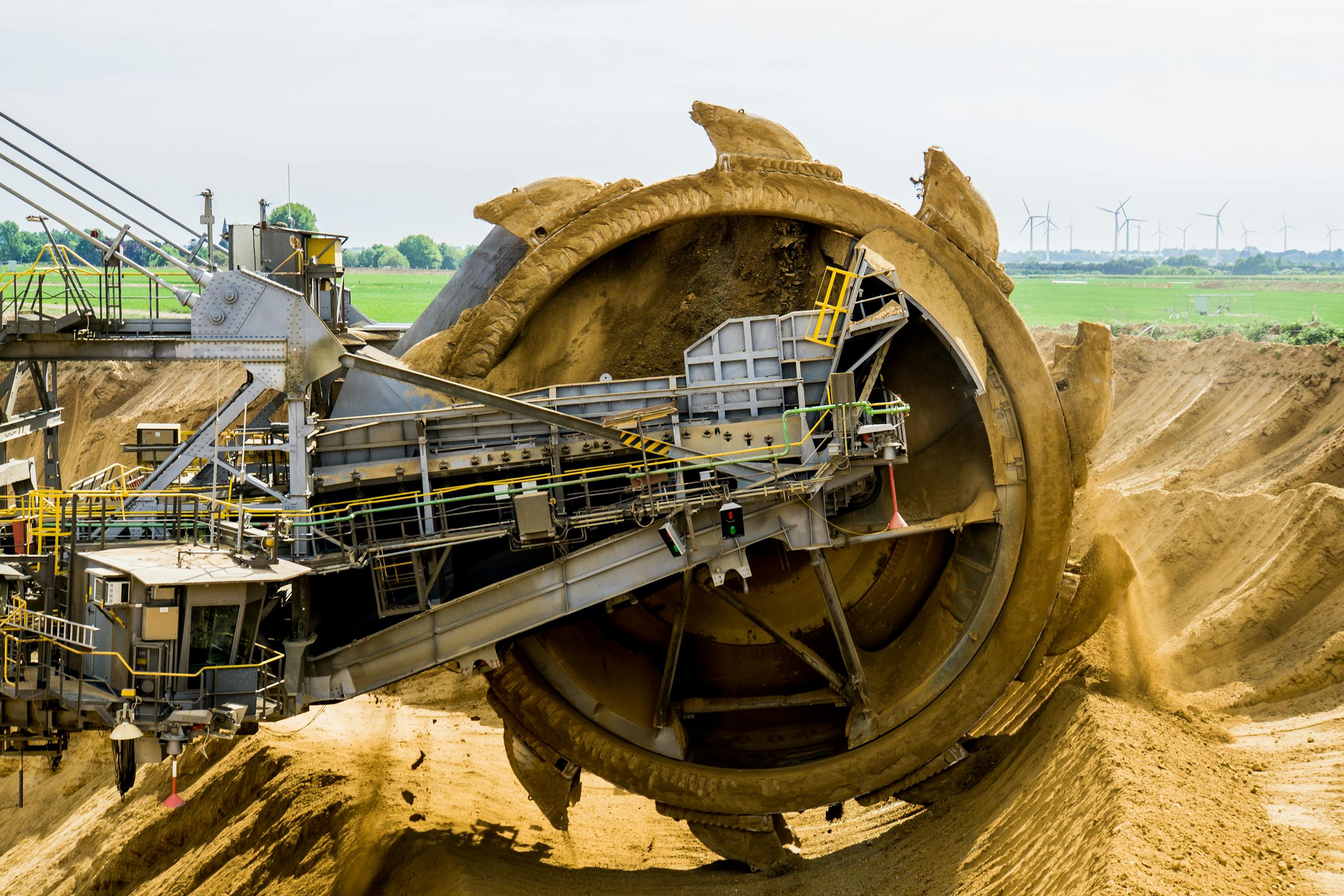 a large bucket wheel excavator working in an open pit mine against a green landscape. 33192 scaled