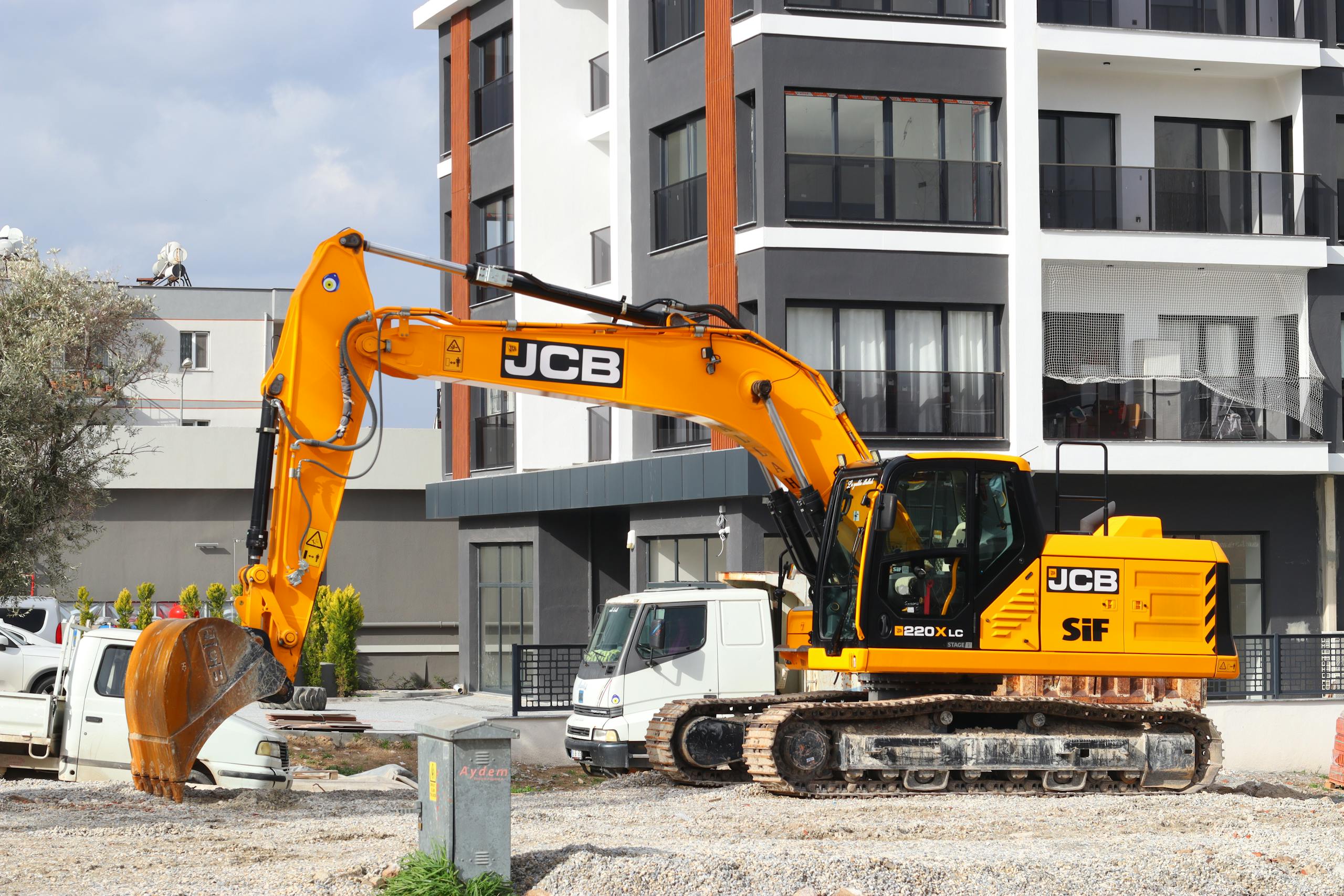 a yellow excavator operating at a city construction site in front of modern buildings. 35846752 scaled