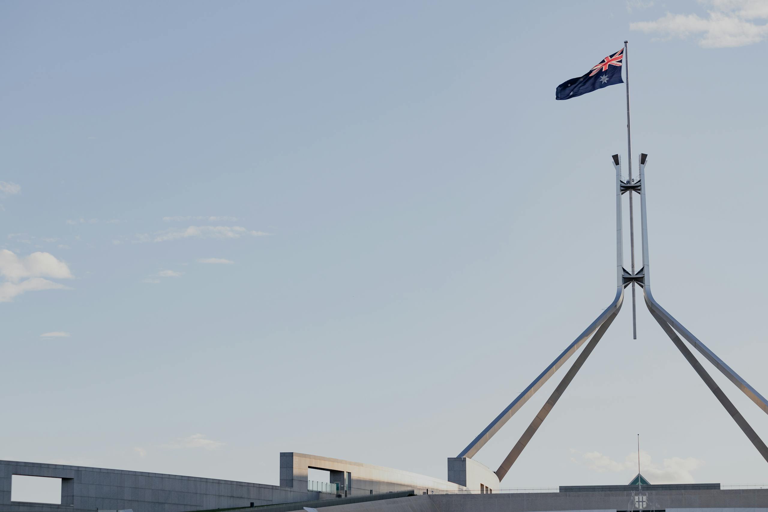 canberras iconic australian parliament house with national flag against a clear blue sky. 12532604 scaled