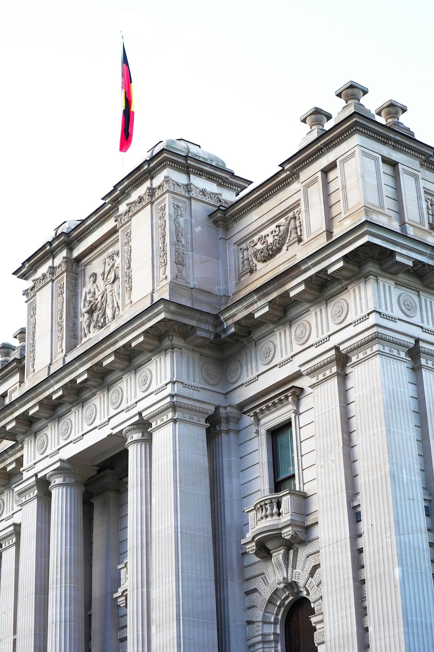 close up of a historic building facade with architectural details and a flag in melbourne australia. 27949349 scaled