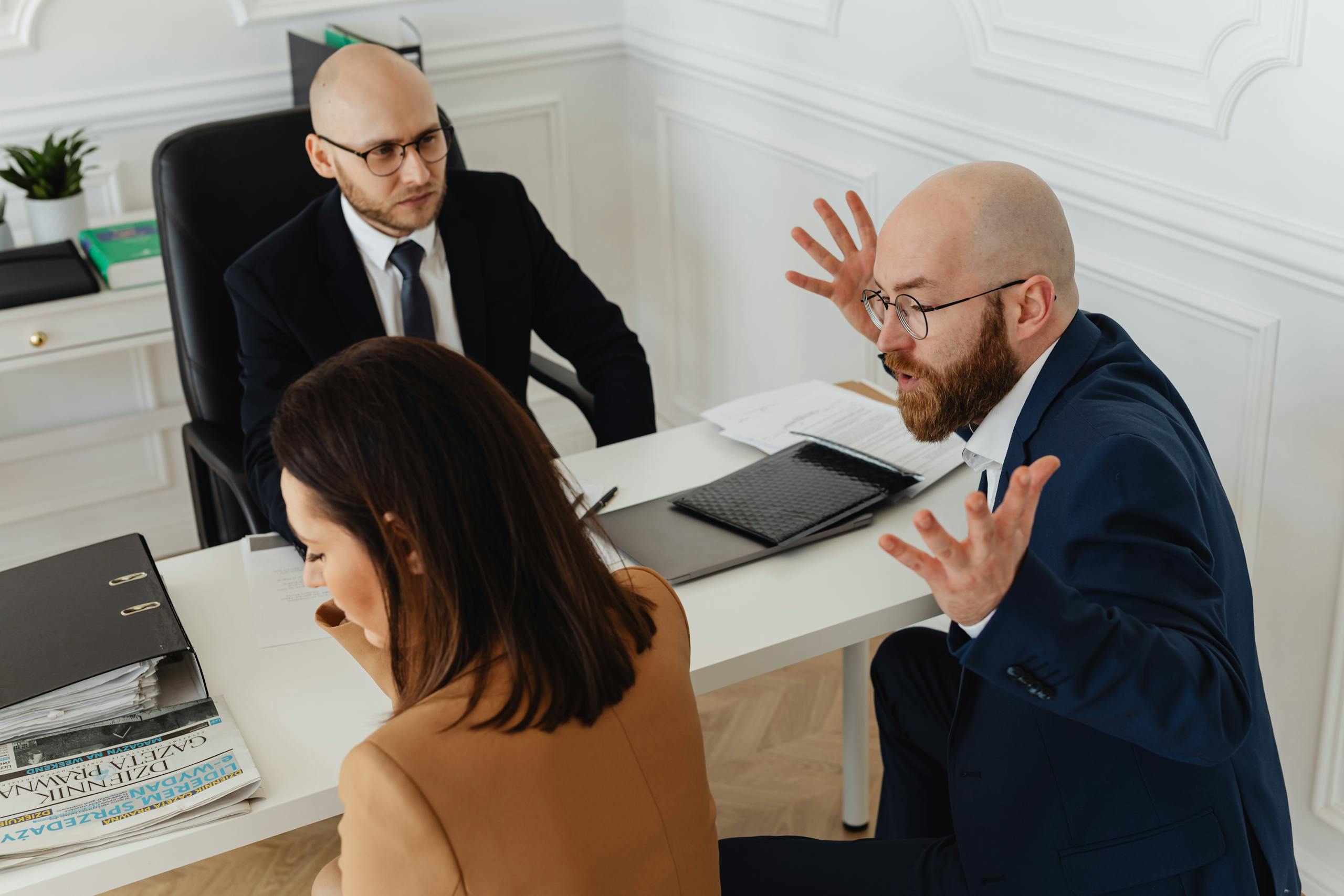 three colleagues in a heated discussion during an office meeting. 7876091 scaled