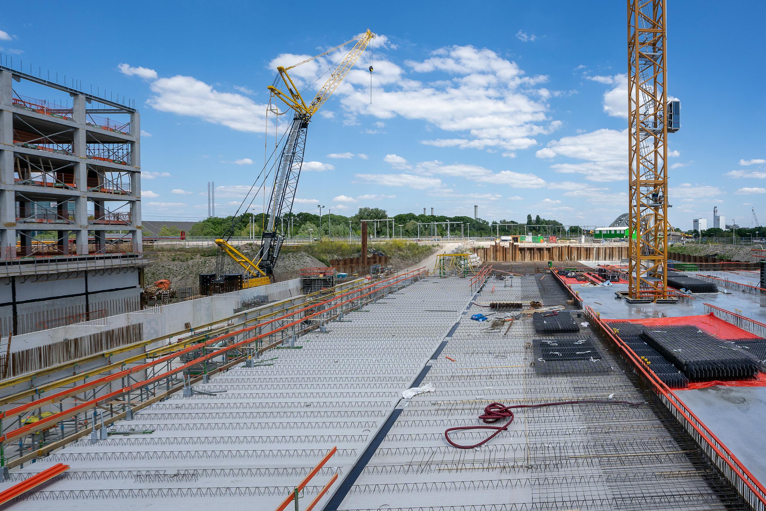 view of a busy construction site with cranes and building structure under clear sky. 5511065 scaled
